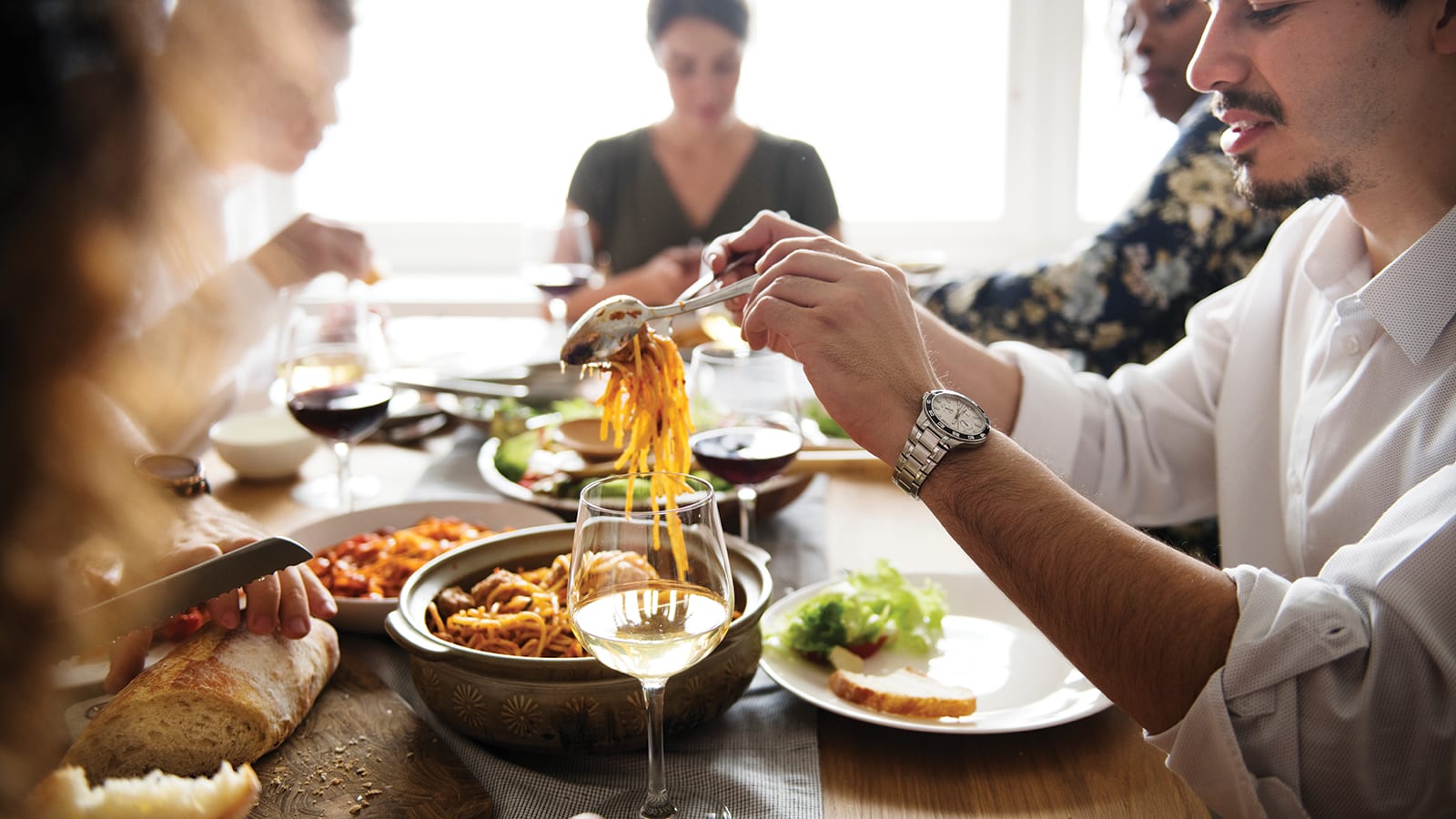 People gathered around the holiday table eating pasta.