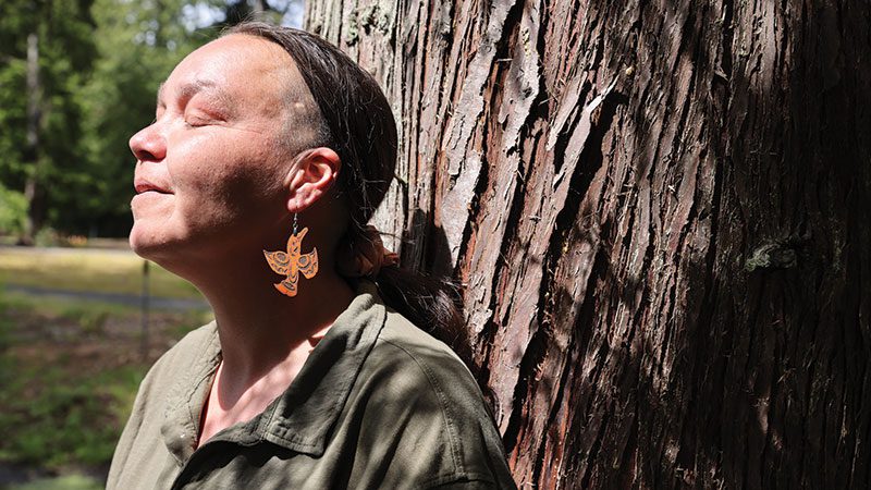 Debby Purser leans against a cedar tree